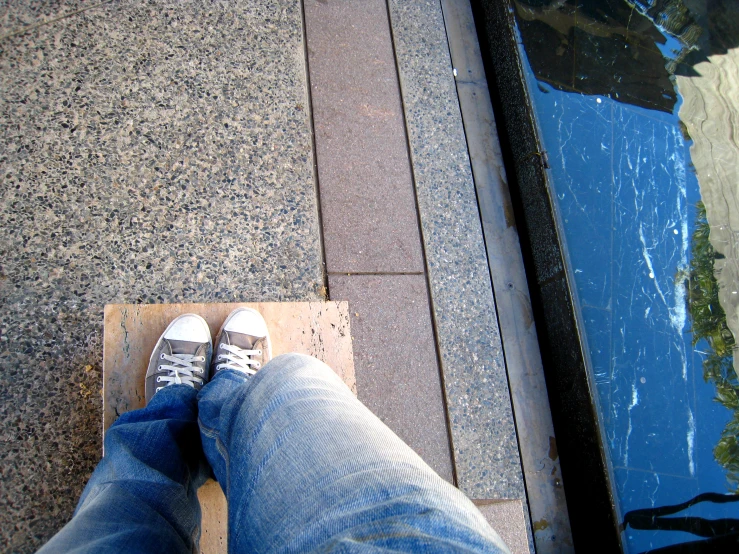 the man is standing on the ground next to the water