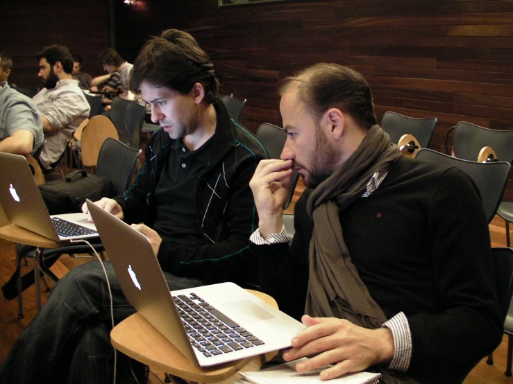 two men in black sitting and using laptop computers