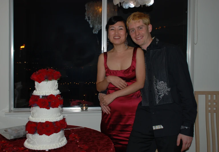 a couple standing in front of a wedding cake