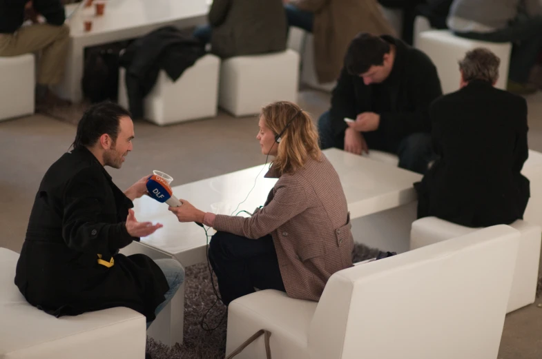 two people talk and hold cups at a table