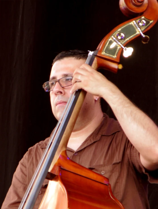 a male in a brown shirt and a cello