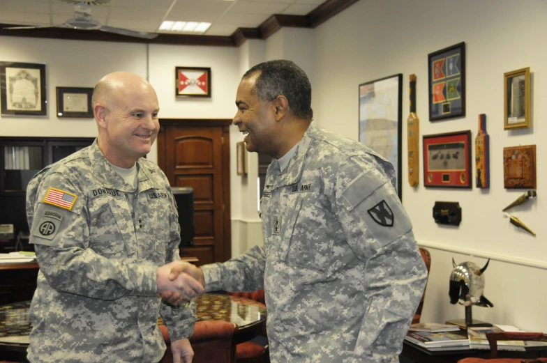 two military officers in camouflage shake hands