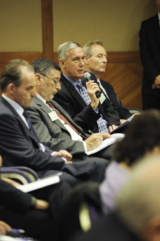 several business people are sitting in front of a microphone