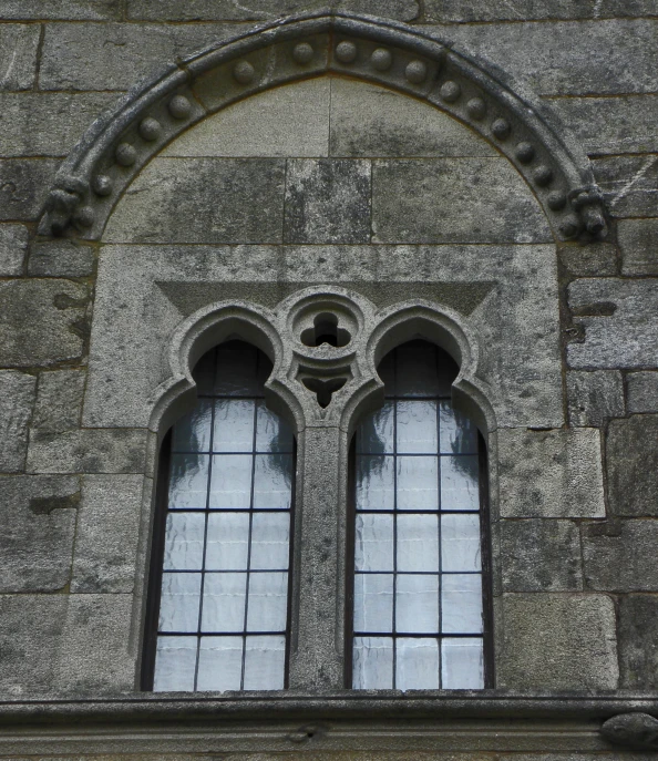 two windows that are next to a stone building