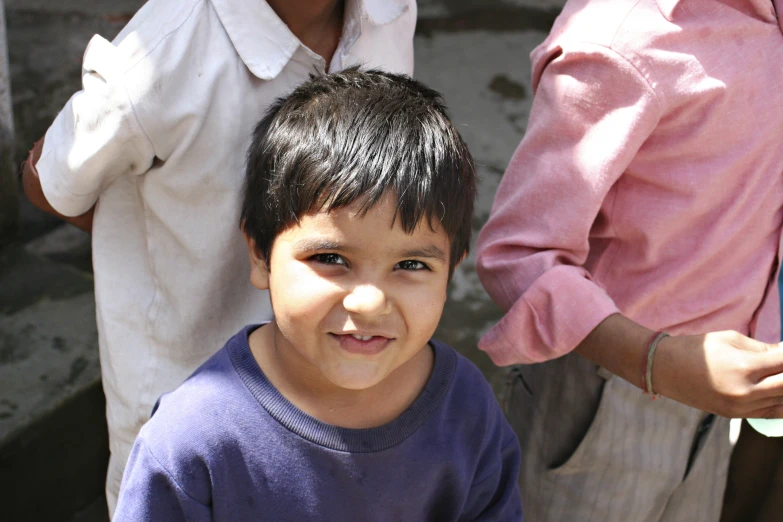 little boy smiling with three people nearby him