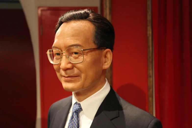 an asian man in glasses and a suit smiles for the camera