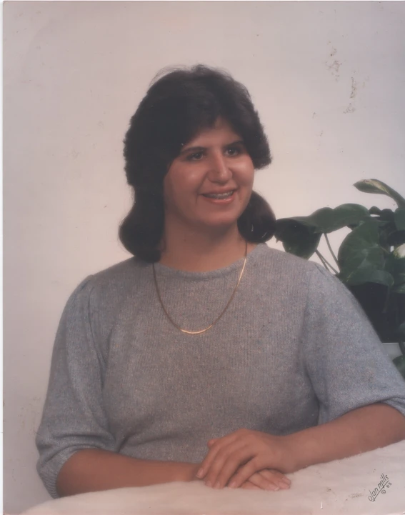 a woman with dark hair smiling in a white space