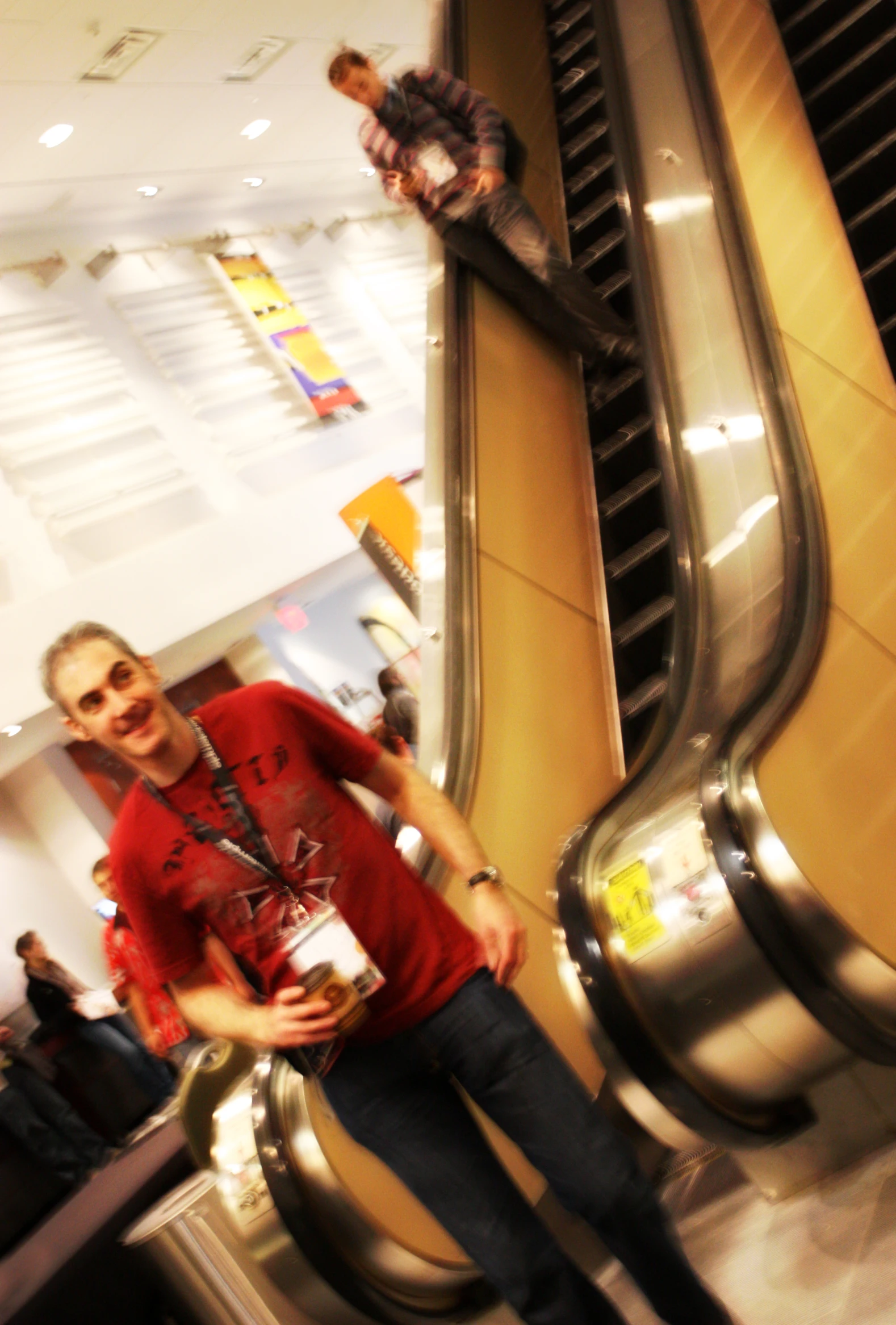 a man in a red shirt is standing with two escalators