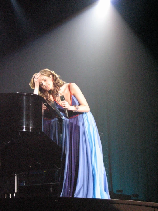 a woman standing at a piano with her head in the air