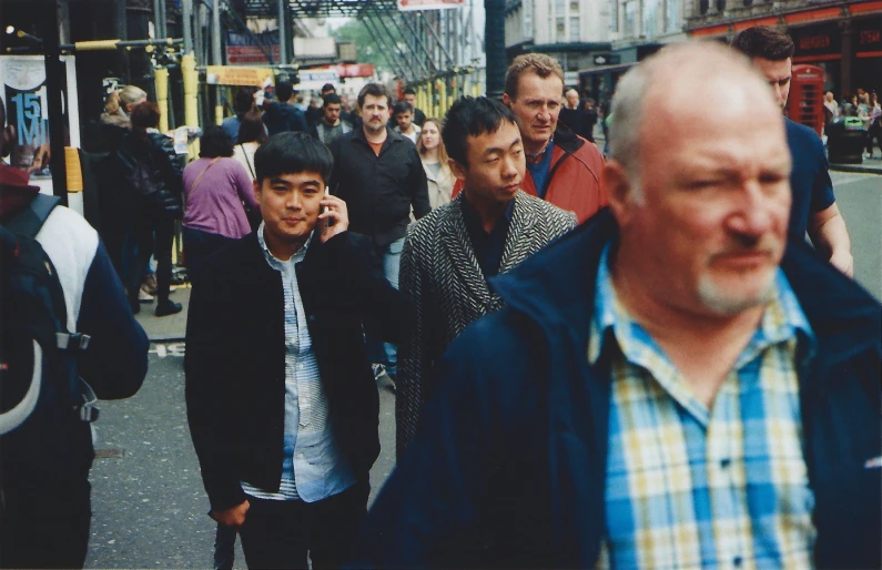 an older man standing in the middle of the street while talking on his cell phone