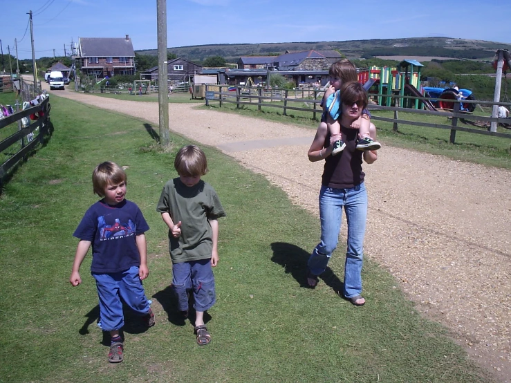 three children on a small gravel path are holding their mother's baby