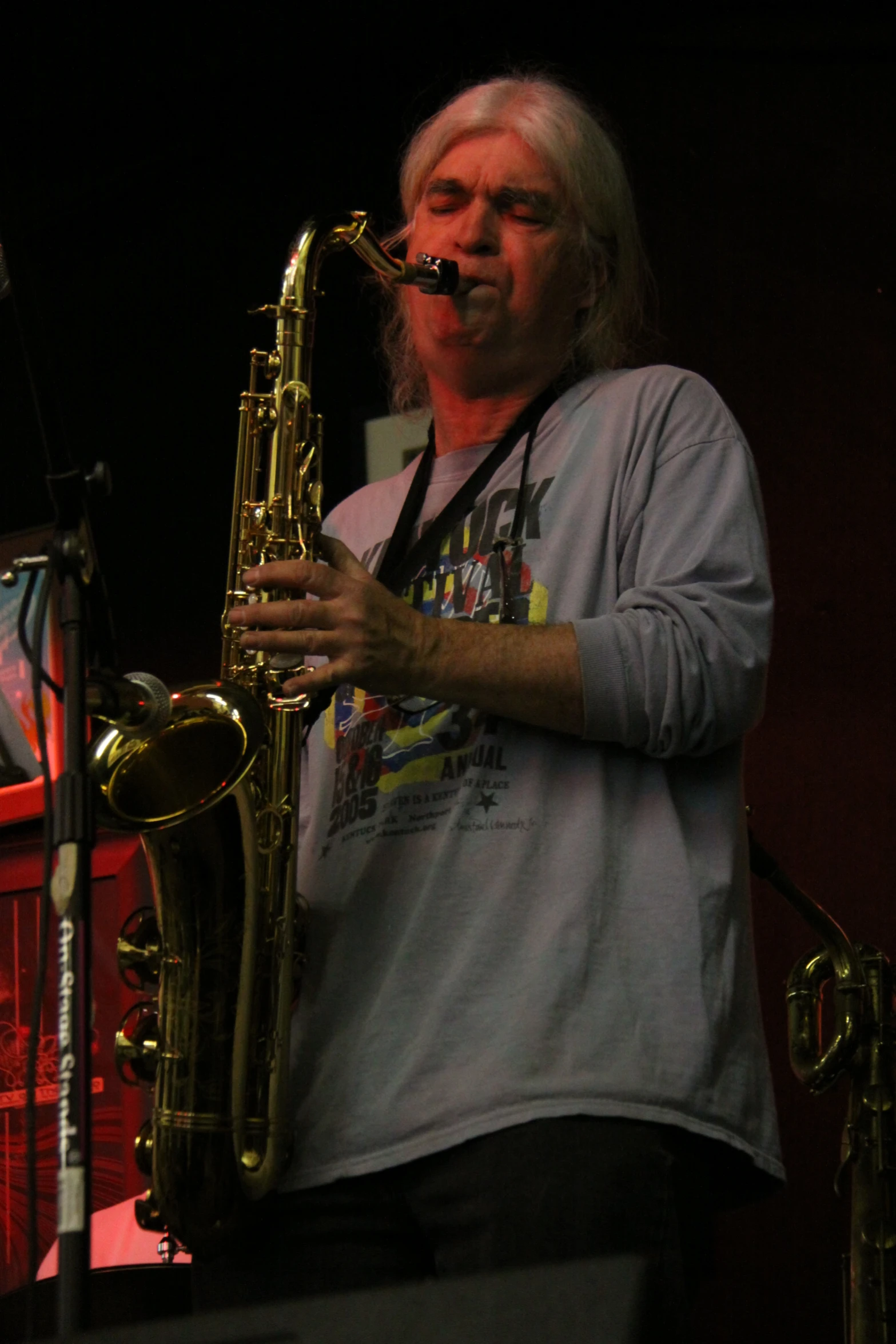 a man holding a saxophone while standing in front of a speaker