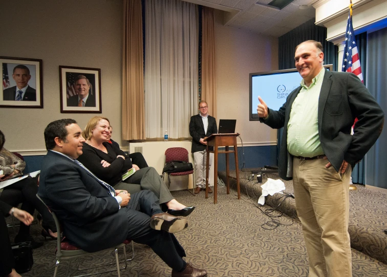 a man with a green shirt and beige pants giving a presentation