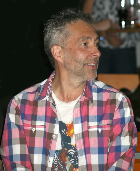 a man wearing a pink and white checkered shirt with a tie sitting next to him