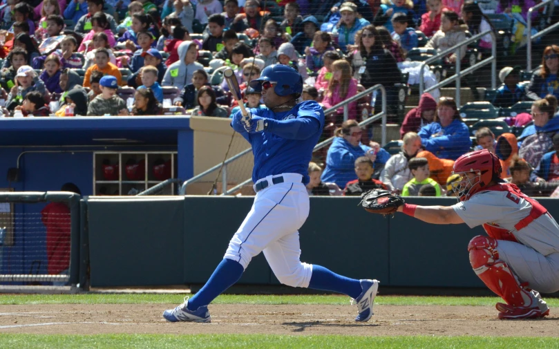 baseball player in blue and white uniform swinging the bat