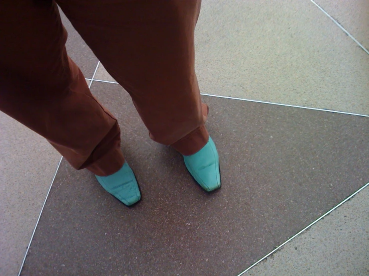 someone with blue shoes standing next to a toilet