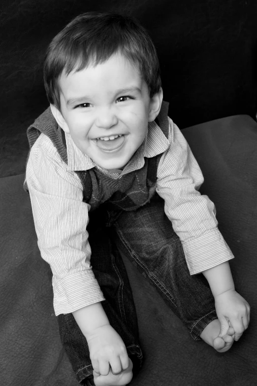 a smiling little boy sitting on the ground