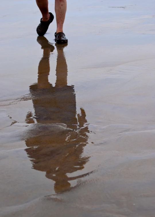 there is a person walking along the beach with a large object in the water