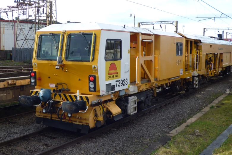 a yellow train engine carrying a cargo cart behind it