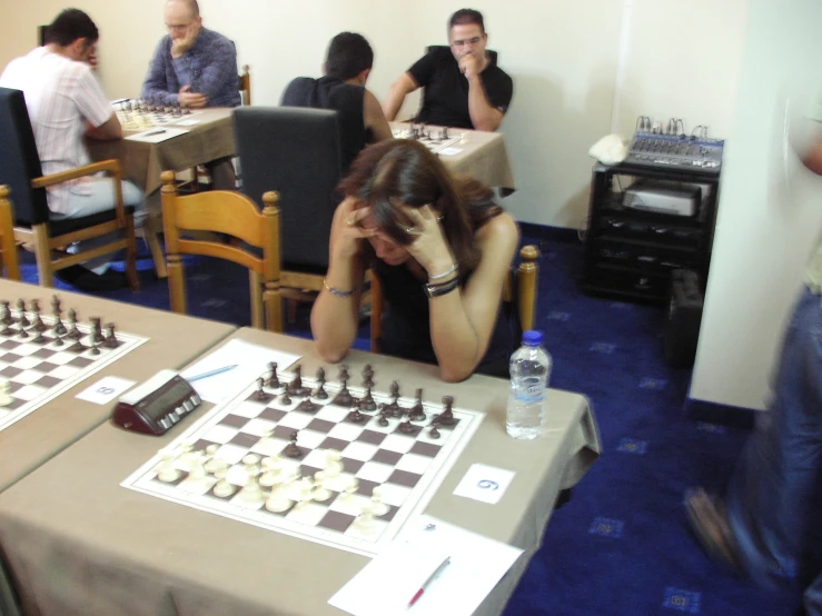 a woman is sitting in front of chess and looking at the board