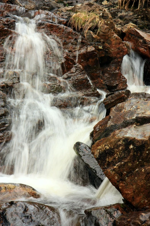 small stream with rock formations and some grass growing on top