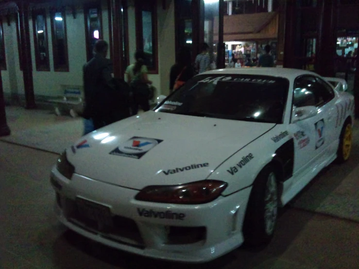 a white car parked outside a building next to a sidewalk