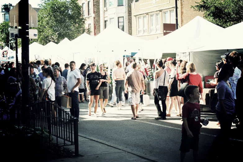 people walking around outside of tent booths in the sun