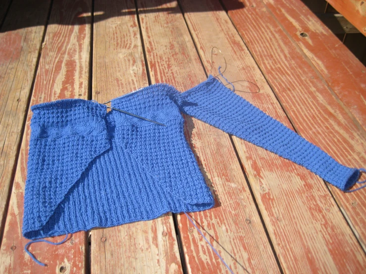 a blue sweater sitting on top of wooden ground