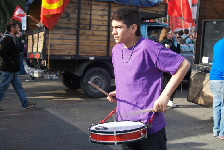 a boy with a large drum in a street