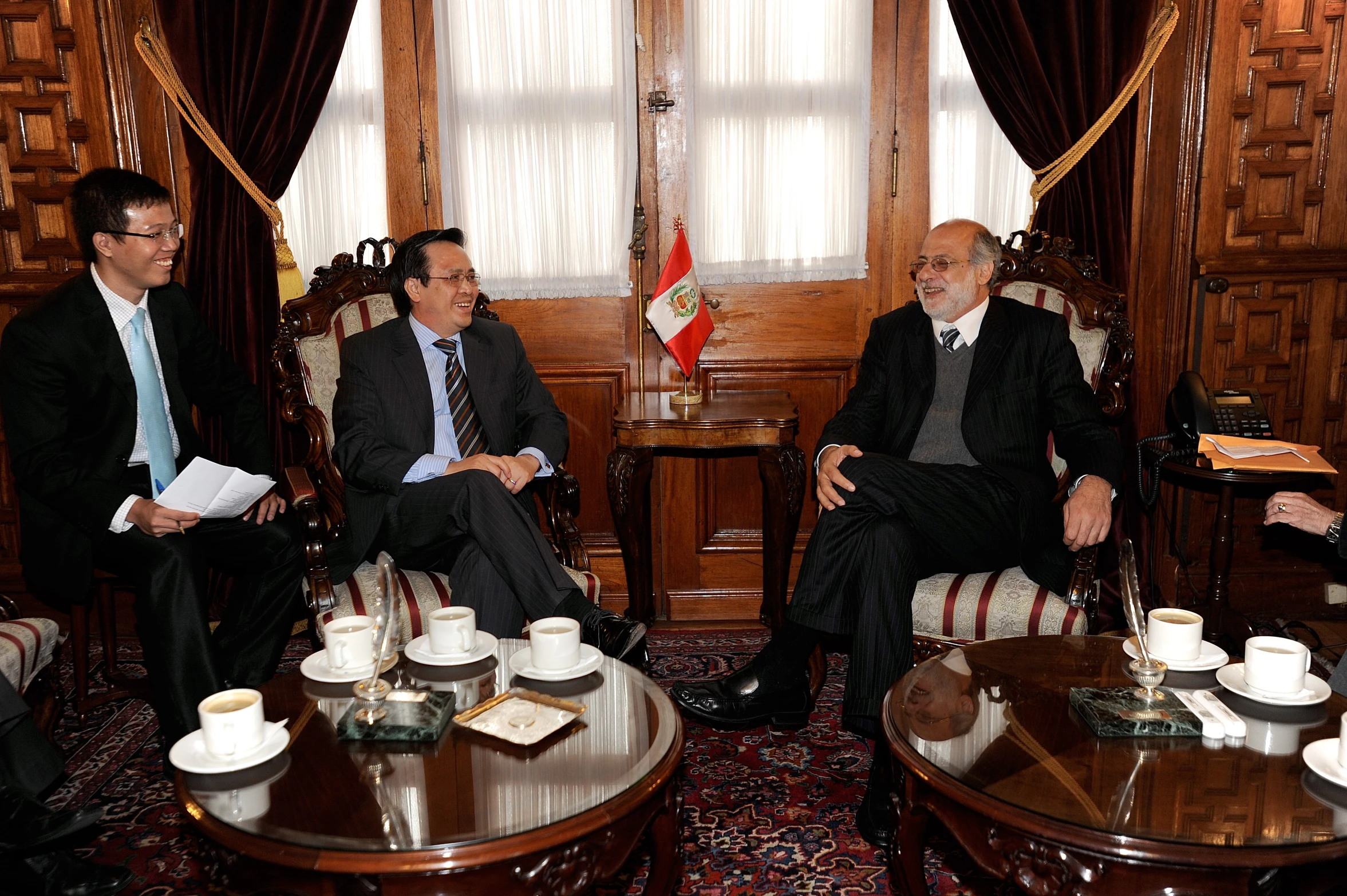 three men are sitting around a coffee table in chairs