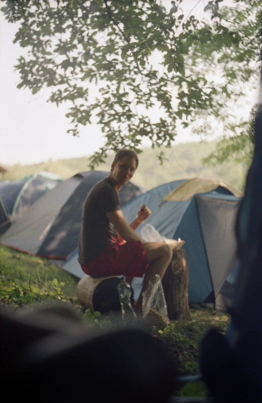 a guy with short shorts sitting in front of tents