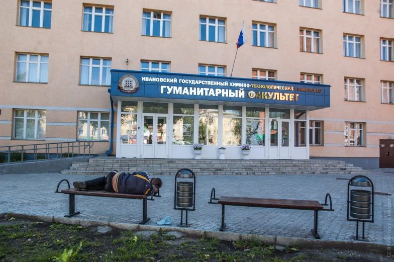 a man sleeps on a bench in front of an apartment building