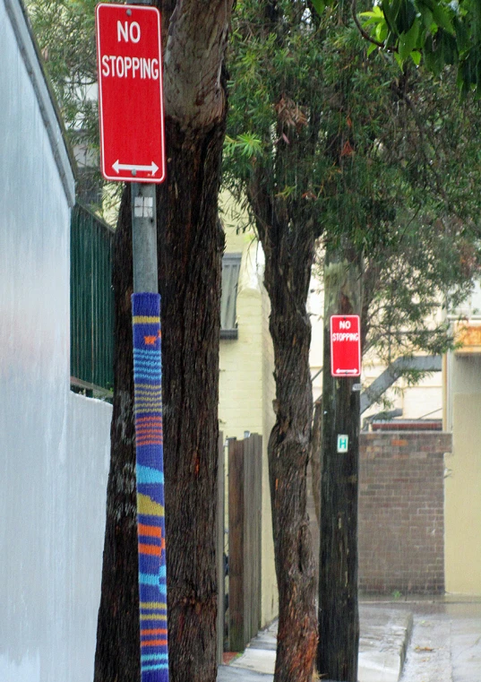 a no stopping sign hangs near a row of trees