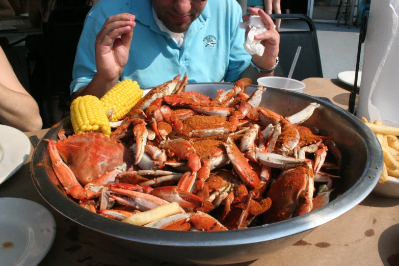 a man eating a large pot full of crab legs