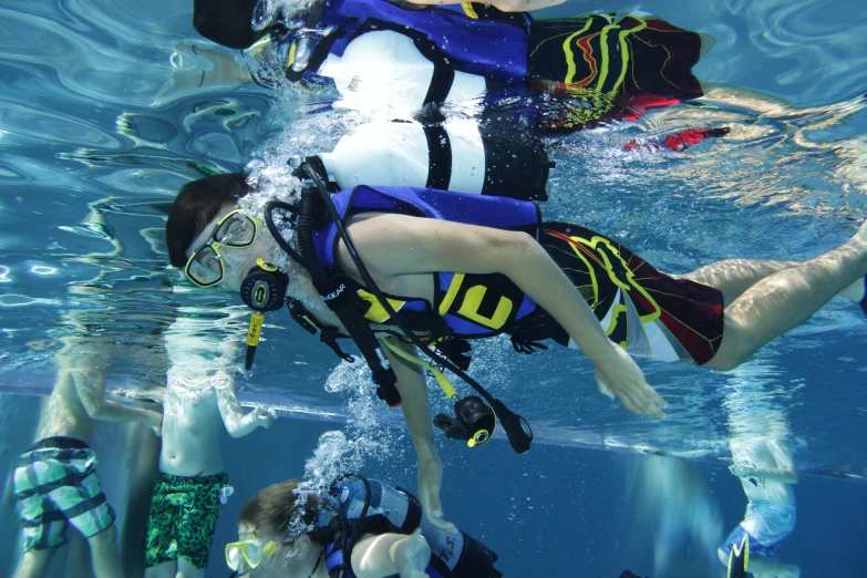 people in wet suits swim in a blue pool