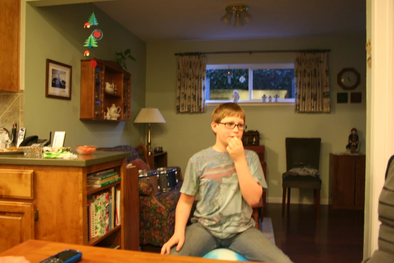 boy in glasses sits in the kitchen of his home