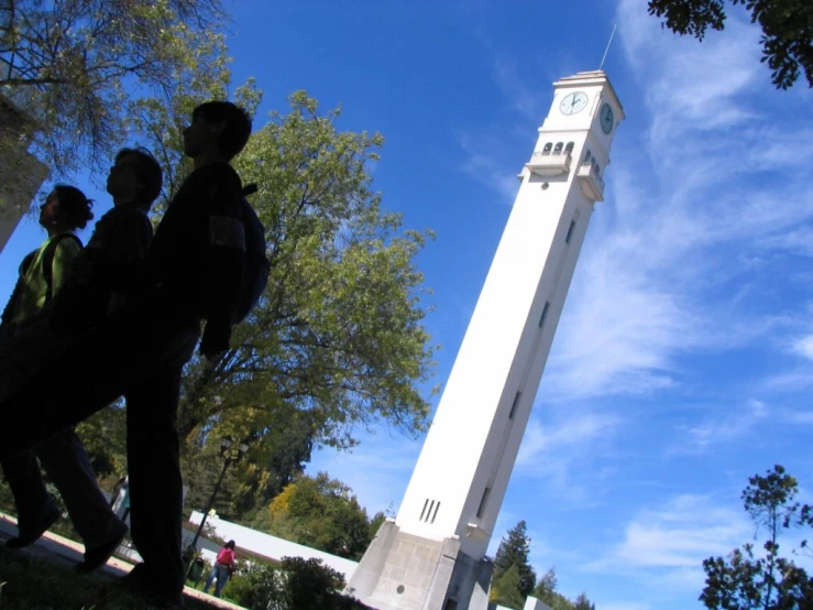 a group of people standing in front of a tall clock tower