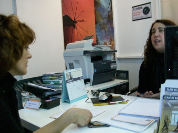 two women at desk, one looking toward printer