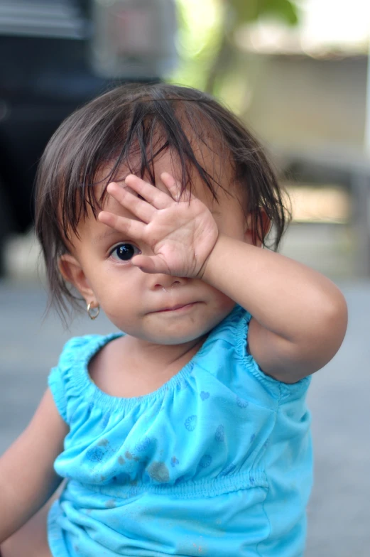 a little girl looking into the camera with her hands on her ears