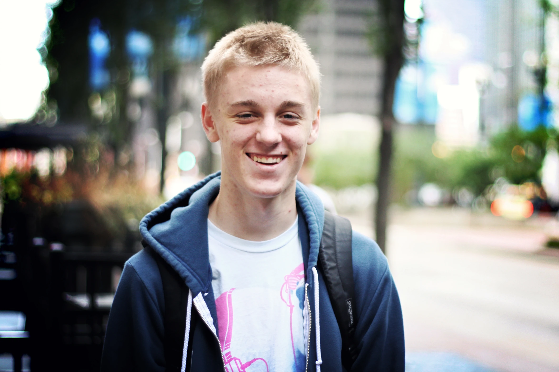 a boy wearing a white t - shirt and a jacket in the street