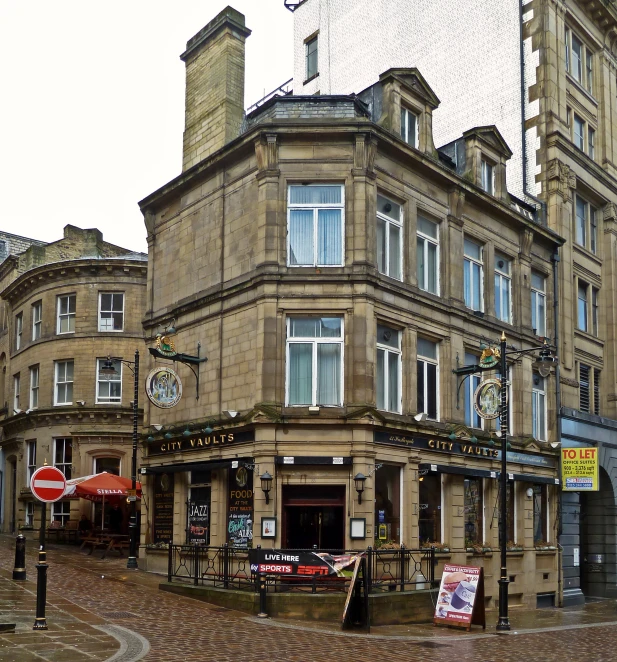 a brown brick building with a street corner cafe and shop front