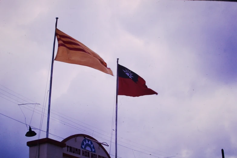 two flags flying in the wind near a clock