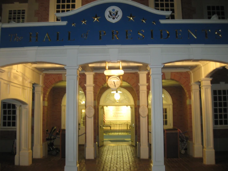 the front entrance to the white building with blue and white letters