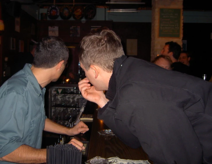 two men are drinking wine together at a bar