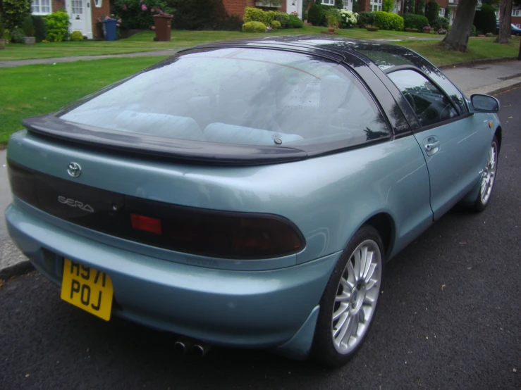 an old fashioned blue sports car sits on the side of the street