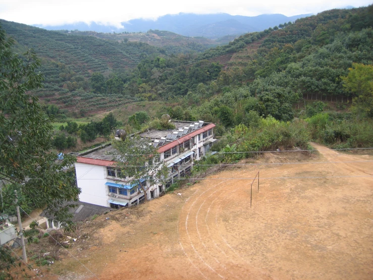 a building is sitting on a hill side with mountains in the background