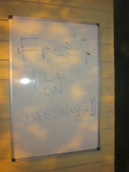 a whiteboard sitting outside of a yellow building
