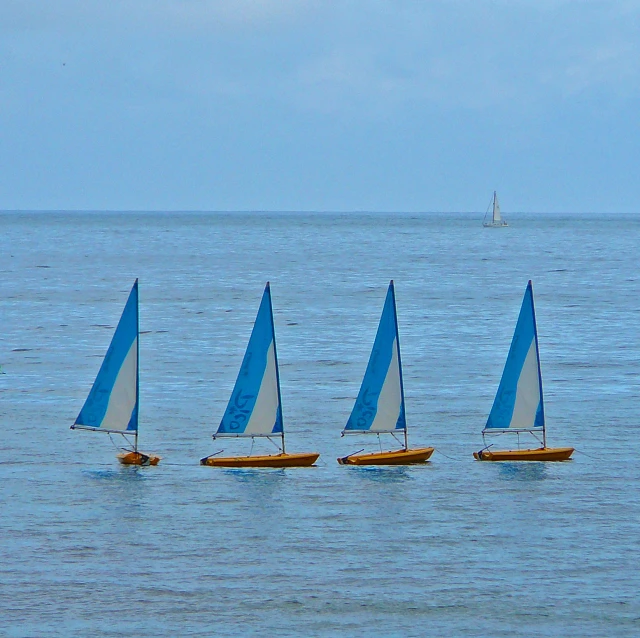 four sailboats are sitting in the ocean on a sunny day