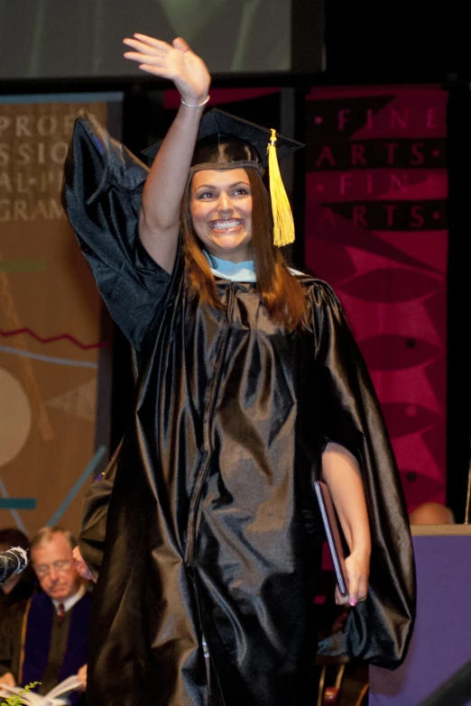 a female in a graduation gown waving