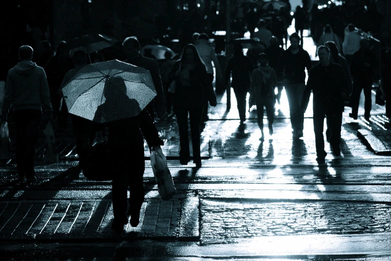 a crowd of people walking down a sidewalk in the rain